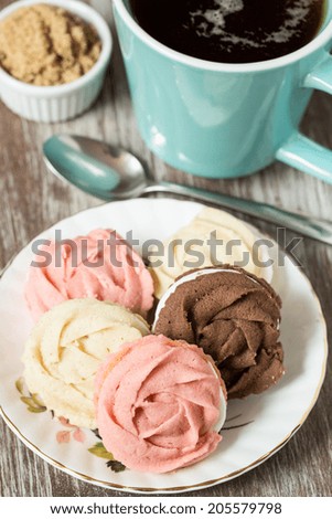 Plate of chocolate vanilla and strawberry cookies with cup of tea and brown sugar and spoon
