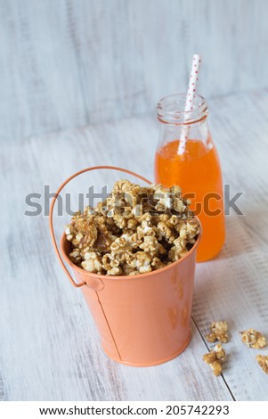 Tin of caramel popcorn with orange soda pop with straw