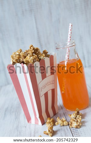 Caramel popcorn snack in bag with orange soda pop with straw