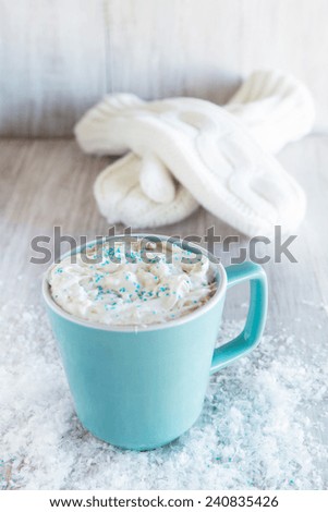 Mug of winter hot chocolate drink with a pair of knit mittens