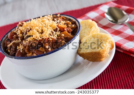 Bowl of warm chili winter comfort food with corn bread muffin and spoon horizontal