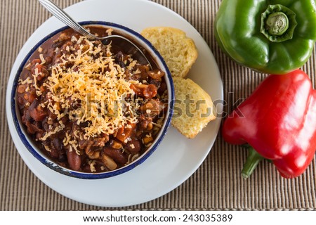 Bowl of warm chili winter comfort food dinner with corn bread muffin red and green peppers