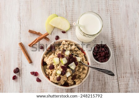 Breakfast cereal oatmeal with cranberries and apples and cinnamon sticks and milk