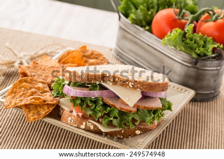 Healthy lunch ham turkey and swiss cheese sandwich with vegetables and chips