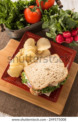 Ham turkey and swiss cheese and onion sandwich with tomato and lettuce and potato chips from above