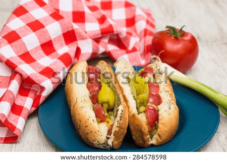 Two delicious Chicago Style hot dogs picnic cookout dinner on blue plate with onion and tomato