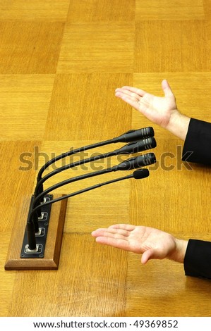 hand of Politician in parliamentary speech, focus on microphones