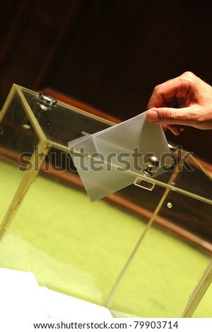 Hand putting a blank ballot inside the box, elections concept