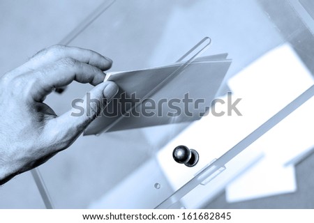 Hand putting a blank ballot inside the box, elections concept, Blue tone