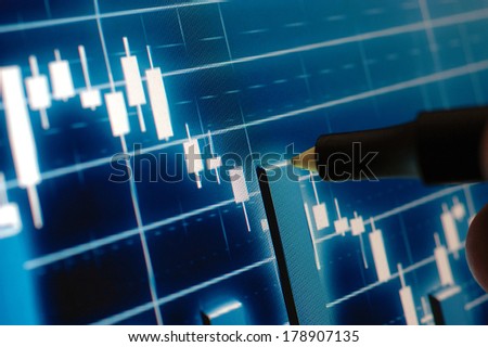 Marker pointing at the stock chart on monitor
