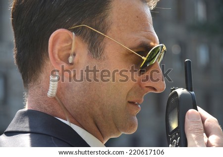 Security guard with glasses and walkie-talkie in his hand