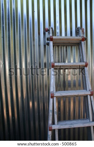 Ladder Against Shiny Silver Corrugated Aluminum Siding Wall