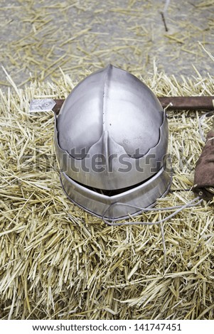 Medieval steel helmet with sword on ground, historical reenactment