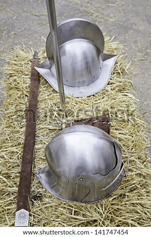 Medieval steel helmet with sword on ground, historical reenactment