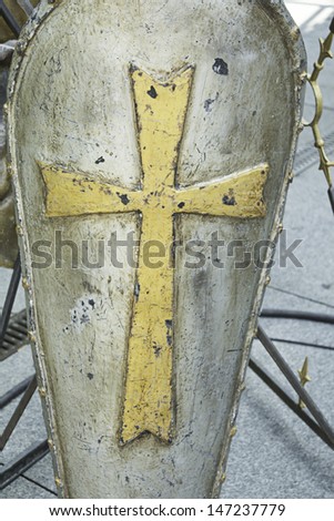 Metal shield with golden cross in medieval festival, recreation