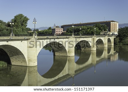 Old bridge over river with blue water, building and landscape