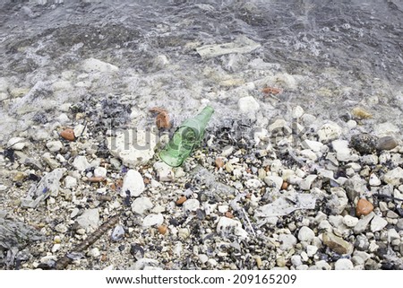 Broken bottle on beach shore, dirt and environment