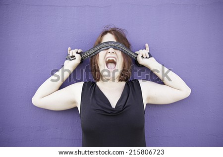 Girl covering eyes with tape on wall, mystery
