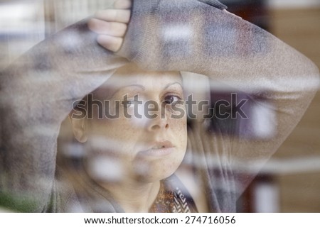 Woman leaning against glass looking sad