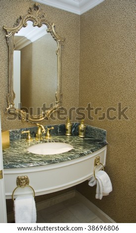 Two brass taps on marble plate sink and baguette framed mirror