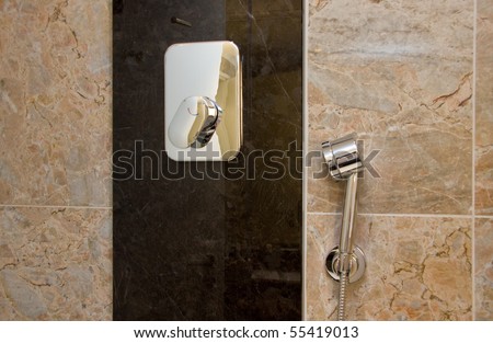Chrome-plated sprinkle shower and  tap for hot and cold water at the bath marble wall