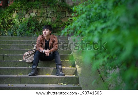 Young man sitting, loneliness, among the nature