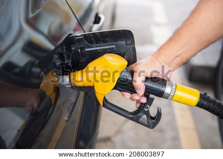 transportation concept - man pumping fuel in car at petrol station