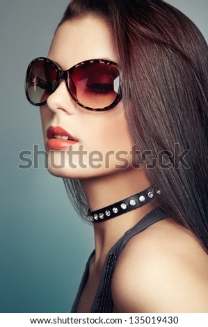 Young beautiful girl in sunglasses. Pretty model poses at studio.