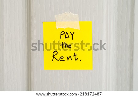 sticky note write a message pay the rent on wood door background
