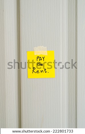 sticky note write a message pay the rent on wood door background
