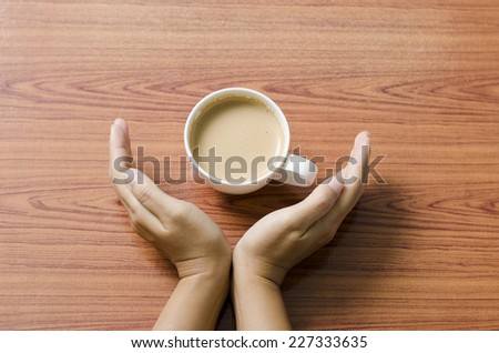 woman hand holding coffee cup on wood table background