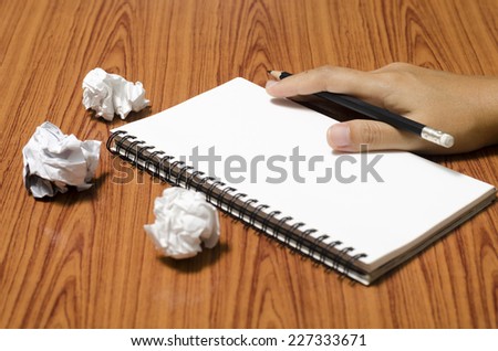 hand writing on notebook with crumpled paper on wood table background
