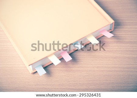 orange book with sticky note on wood background vintage style