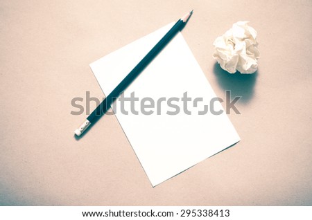 Pencil on clear white paper with crumble paper balls on brown color background vintage style