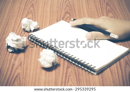 hand writing on notebook with crumpled paper on wood table background vintage style