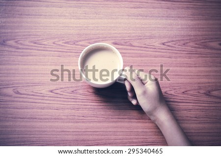 woman hand holding coffee cup on wood table background vintage style