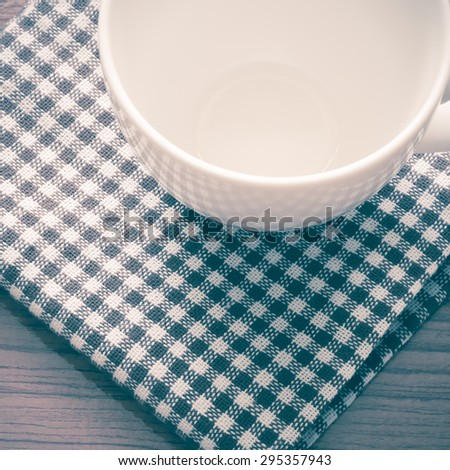 empty coffee cup on brown kitchen towel and wood table vintage style