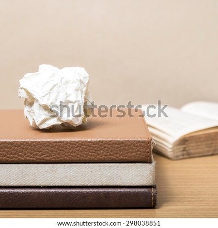 book and crumpled paper on wood background