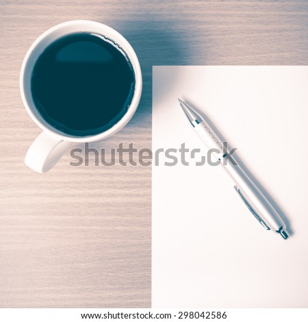 coffee cup with white paper and pen on wood background vintage style