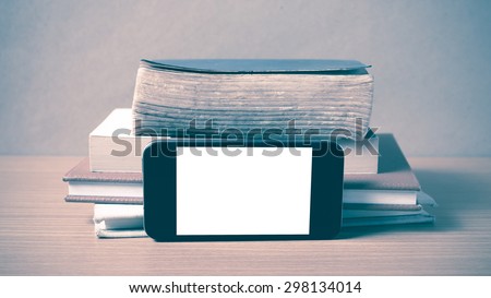 stack of book and smart phone on wood background vintage style