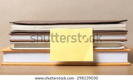 stack of book with sticky note on wood background