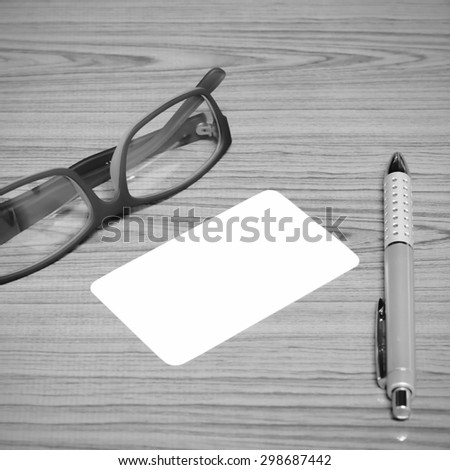 business card and pen with glasses on wood background black and white color tone style