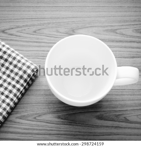 empty coffee cup on brown kitchen towel and wood table black and white color tone style