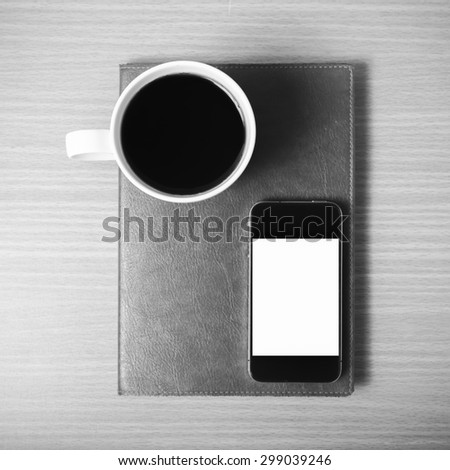 smart phone and coffee cup on book on wood background black and white color tone style