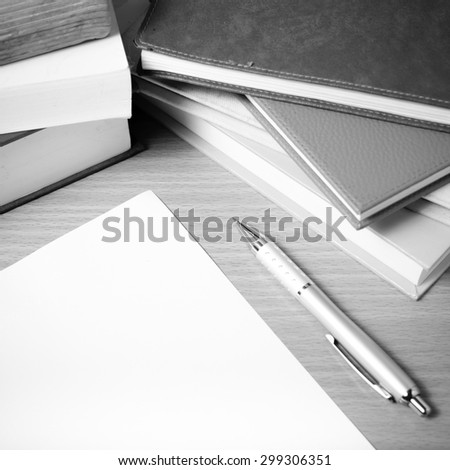 empty paper and pen with book on wood background black and white tone style