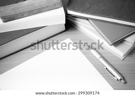 empty paper and pen with book on wood background black and white tone style