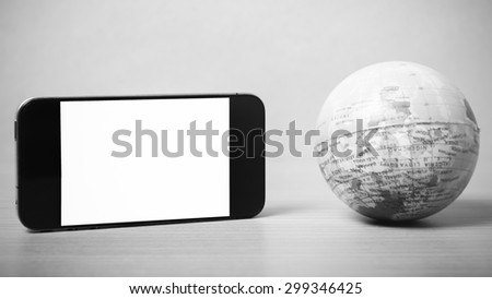 smart phone and earth ball on wood background black and white color tone style