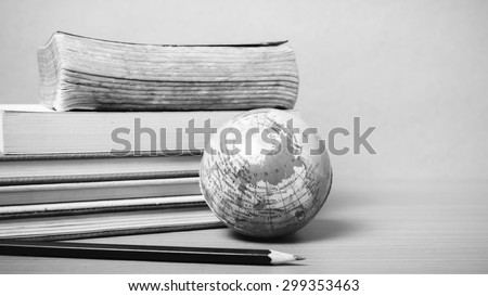 book and earth ball with black pencil on wood background black and white color tone style