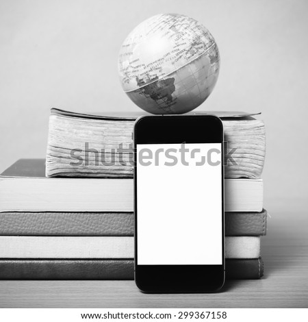 book and earth ball with smart phone on wood background black and white color tone style