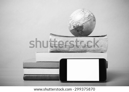 book and earth ball with smart phone on wood background black and white color tone style